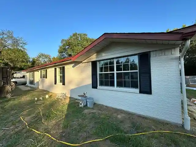 Painted white brick ranch house with red fascia and black shutters