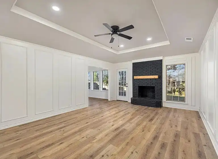 Living room with wainscot panelling, a tray ceiling and a black brick fireplace