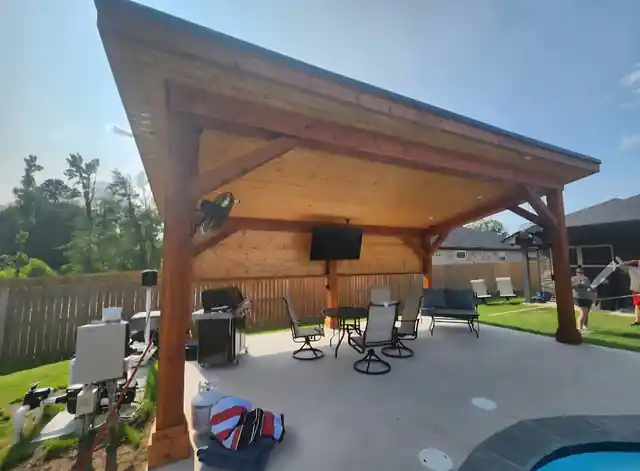 Cedar patio cover with a television beside a pool and lounge furniture