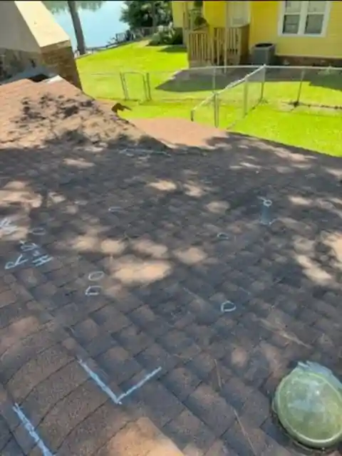 Chalk circles marking hail hits on shingles during an inspection