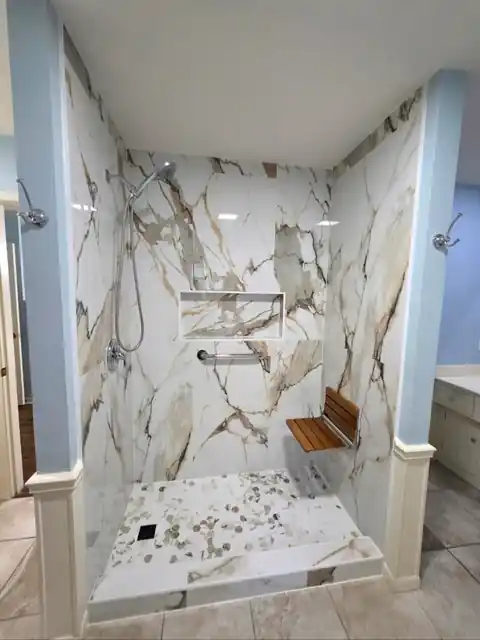 Calacatta-look tile shower with a teak fold-down seat and a recessed niche